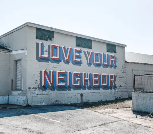 A mural reading “Love Your Neighbor” on the side of a building.